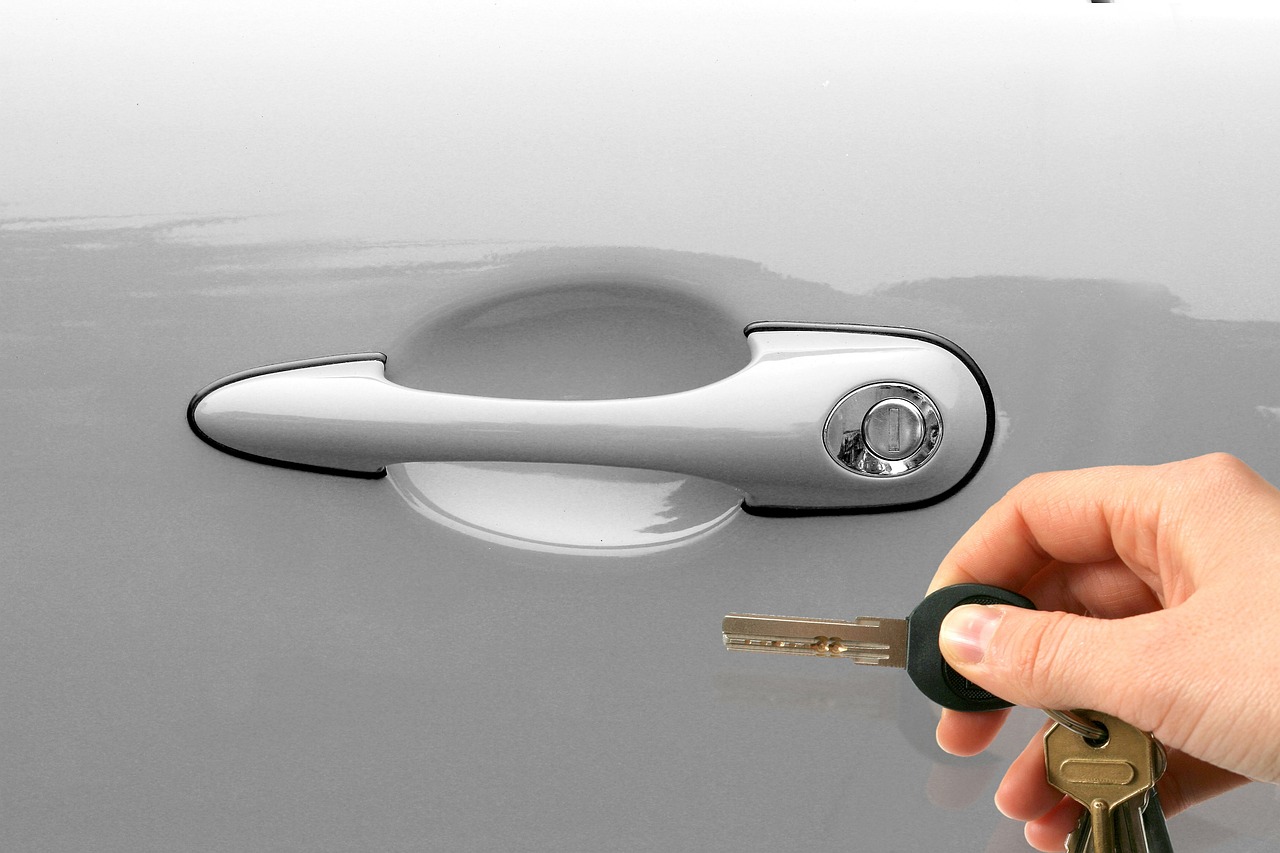 A person holding car keys next to a silver door handle