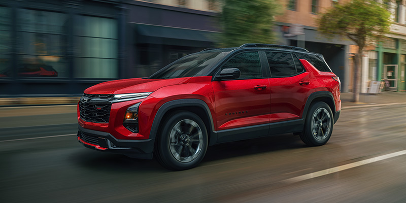 Red Chevrolet Equinox SUV driving through a city street.